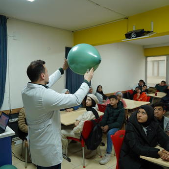 Picture of a teacher holding a balloon in front of students