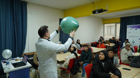 Picture of a teacher holding a balloon in front of students