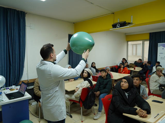 Picture of a teacher holding a balloon in front of students